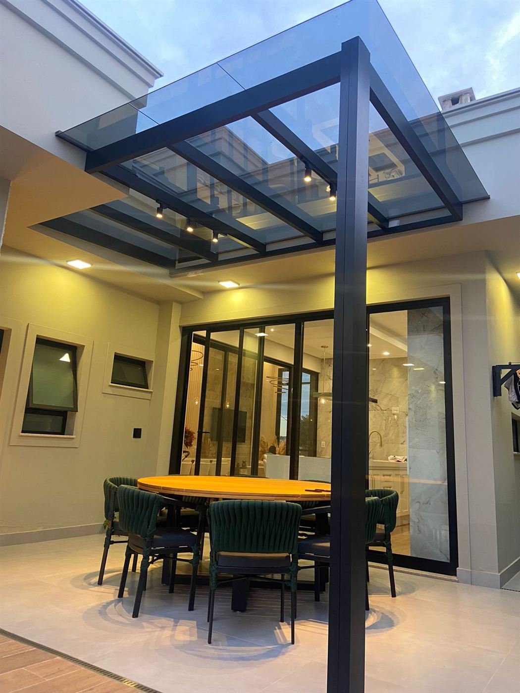 Pérgola de vidro sobre área gourmet com porta de alumínio